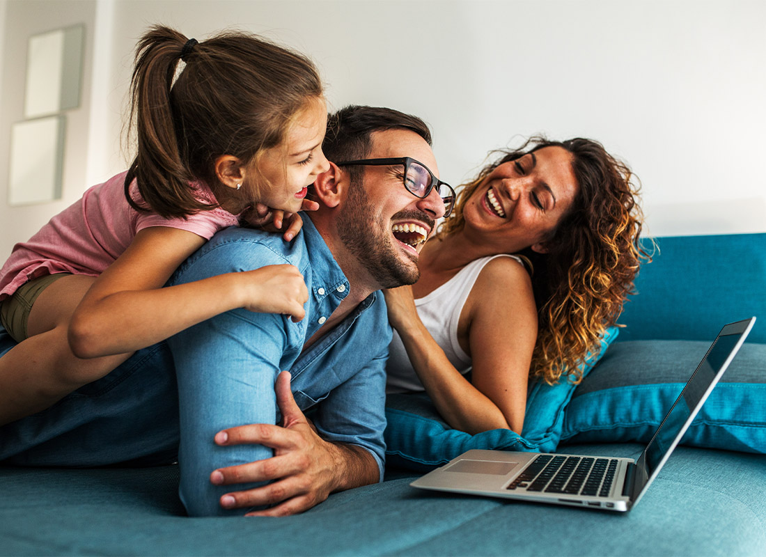 Life Insurance - A Young Family Having Fun Together and Watching Something on a Laptop